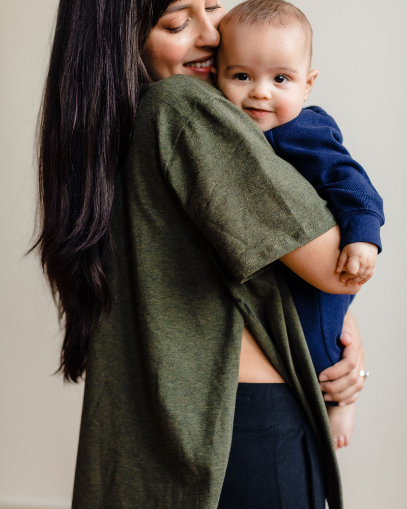 Nursing mother wearing a heather green maternity shirt for stylish comfort